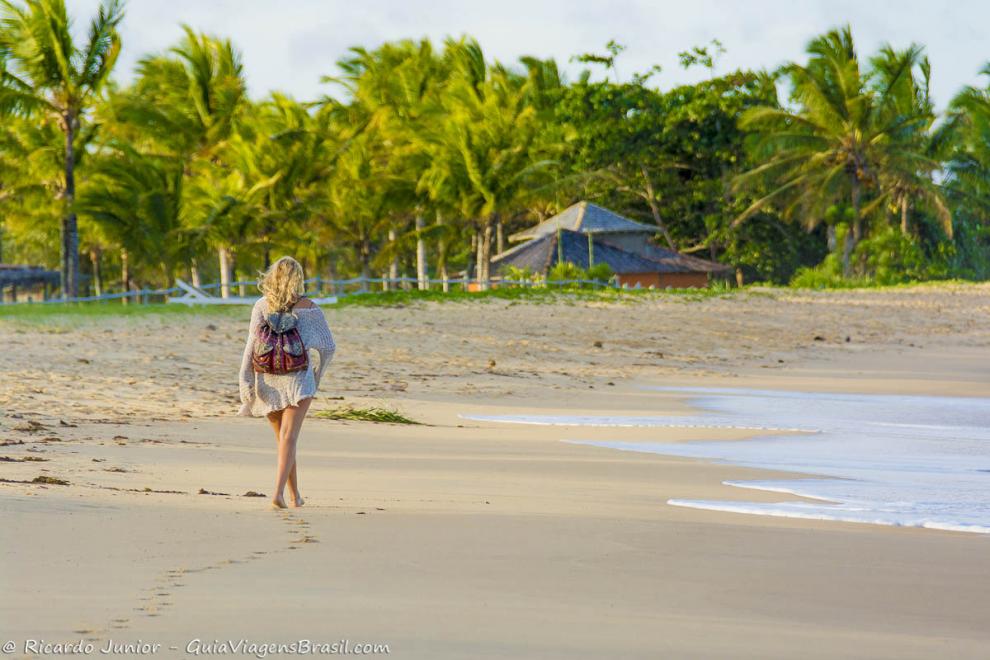 Imagem uma moça loira andando pelas areias da Praia de Caraiva.